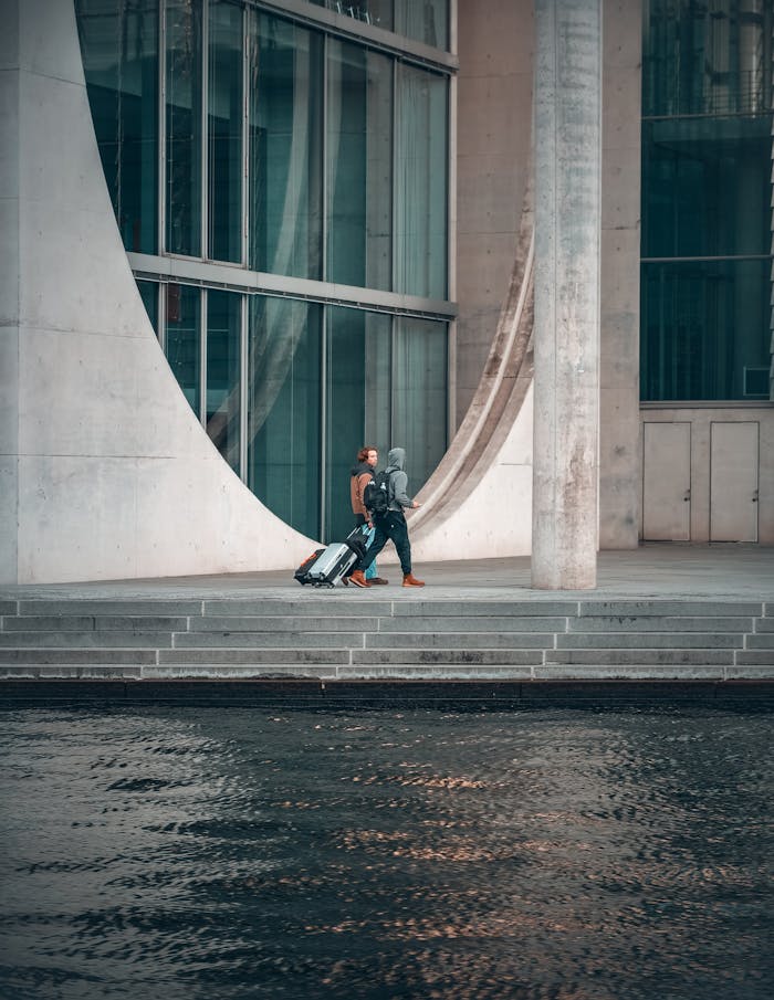 Two tourists walking with suitcases by Marie-Elisabeth-Lüders Haus in Berlin.