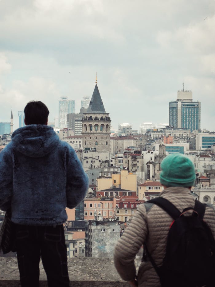 Two people admire the historic Galata Tower skyline in Istanbul, Turkey.