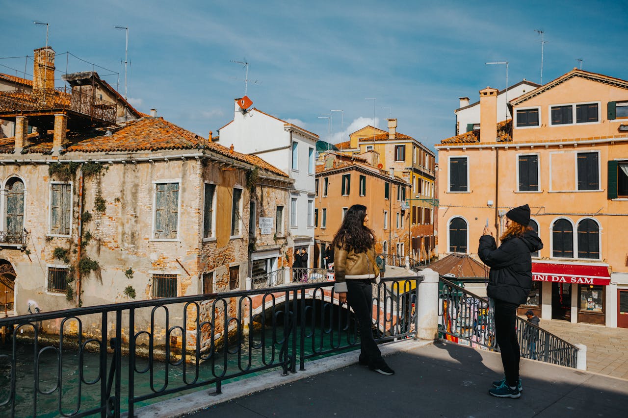 about-01 Two tourists admire the scenic architecture and waterways of Venice, Italy on a sunny day.