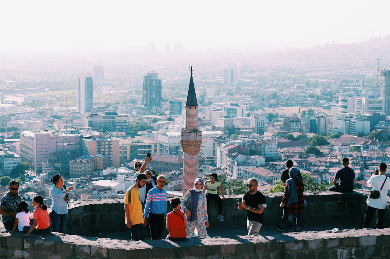 Tourists explore a historic site in Ankara with a panoramic city view, capturing blend of heritage and urban life.